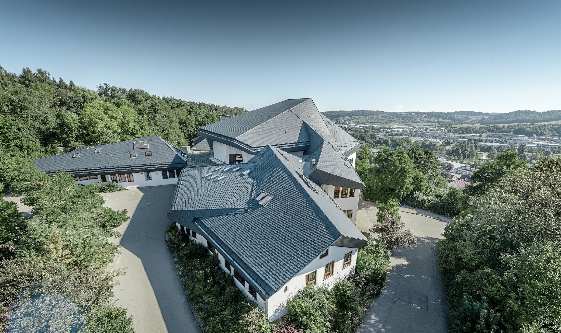 Vrije school in Heidenheim (Duitsland) met groot en onregelmatig dakvlak gerenoveerd met PREFA-dakschindels in antraciet