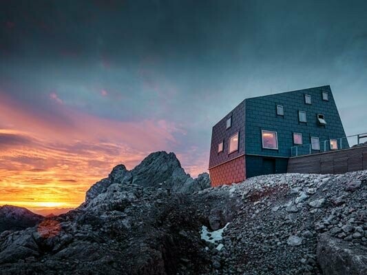 Buitengewone architectuur in de bergen: de Seethalerhütte op de Dachstein bekleed met PREFA dak- en gevelpaneel FX.12 in steengrijs.