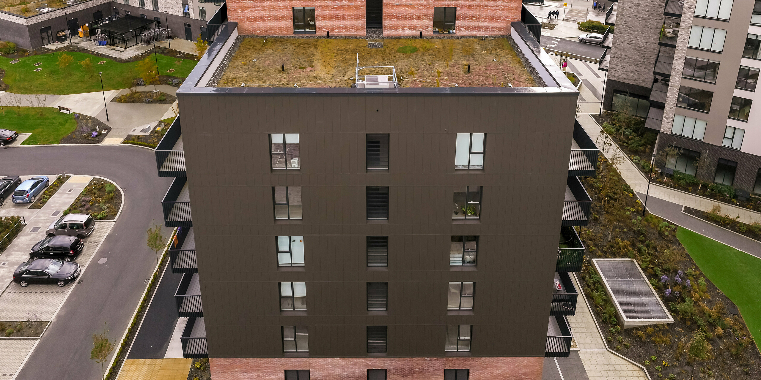 Seitenansicht der Citywest Apartments in Dublin. Die vertikal verlegten PREFA Sidings in P.10 Braun auf ca. 700 m² ergänzen die traditionelle Backsteinfassade. Moderne Architektur und langlebige Aluminiumfassade verbinden ansprechendes Design mit Witterungsbeständigkeit.