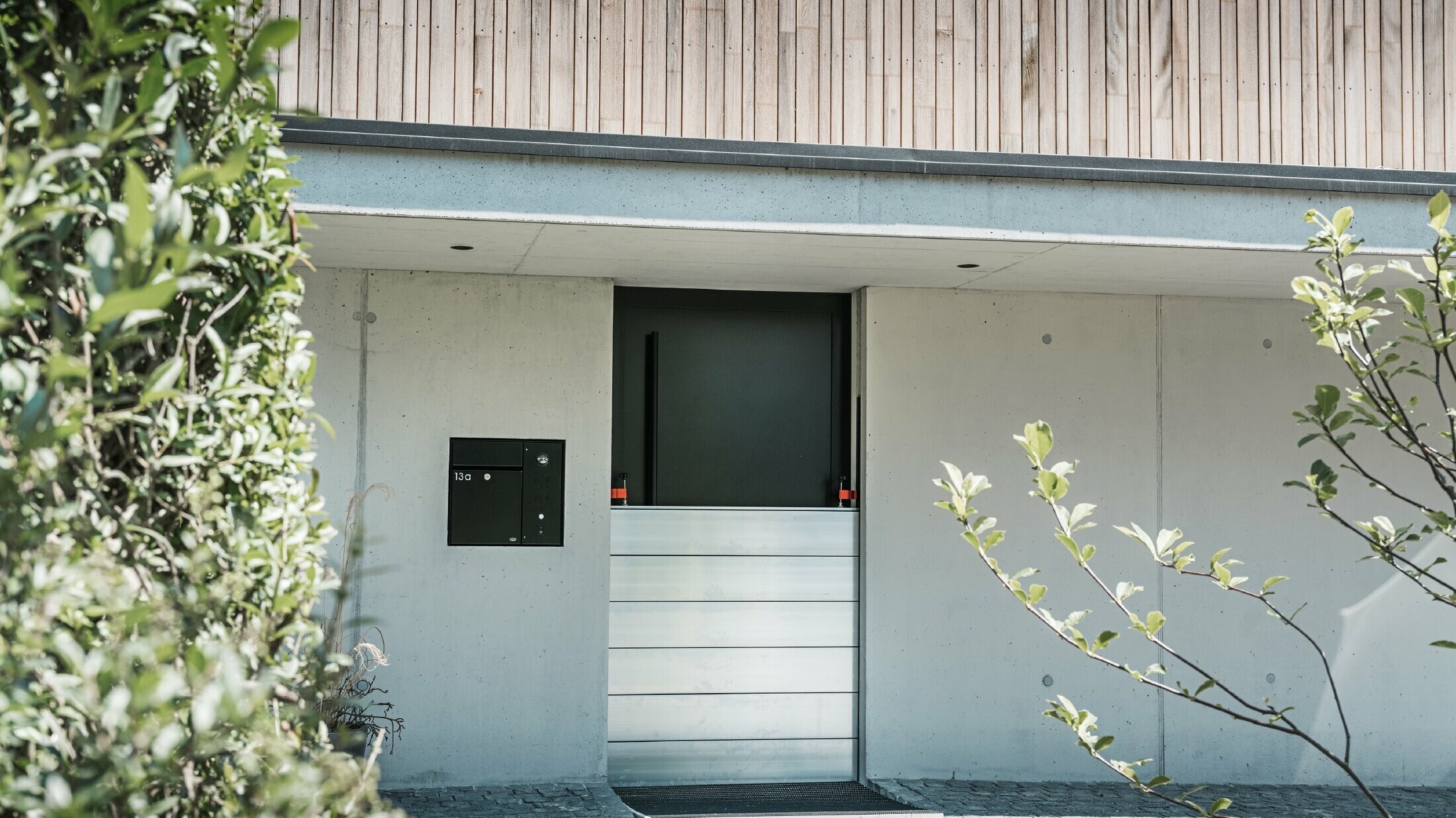 PREFA-hoogwaterbescherming is geïnstalleerd voor de toegangsdeur van een vrijstaand huis met een houten gevel. 