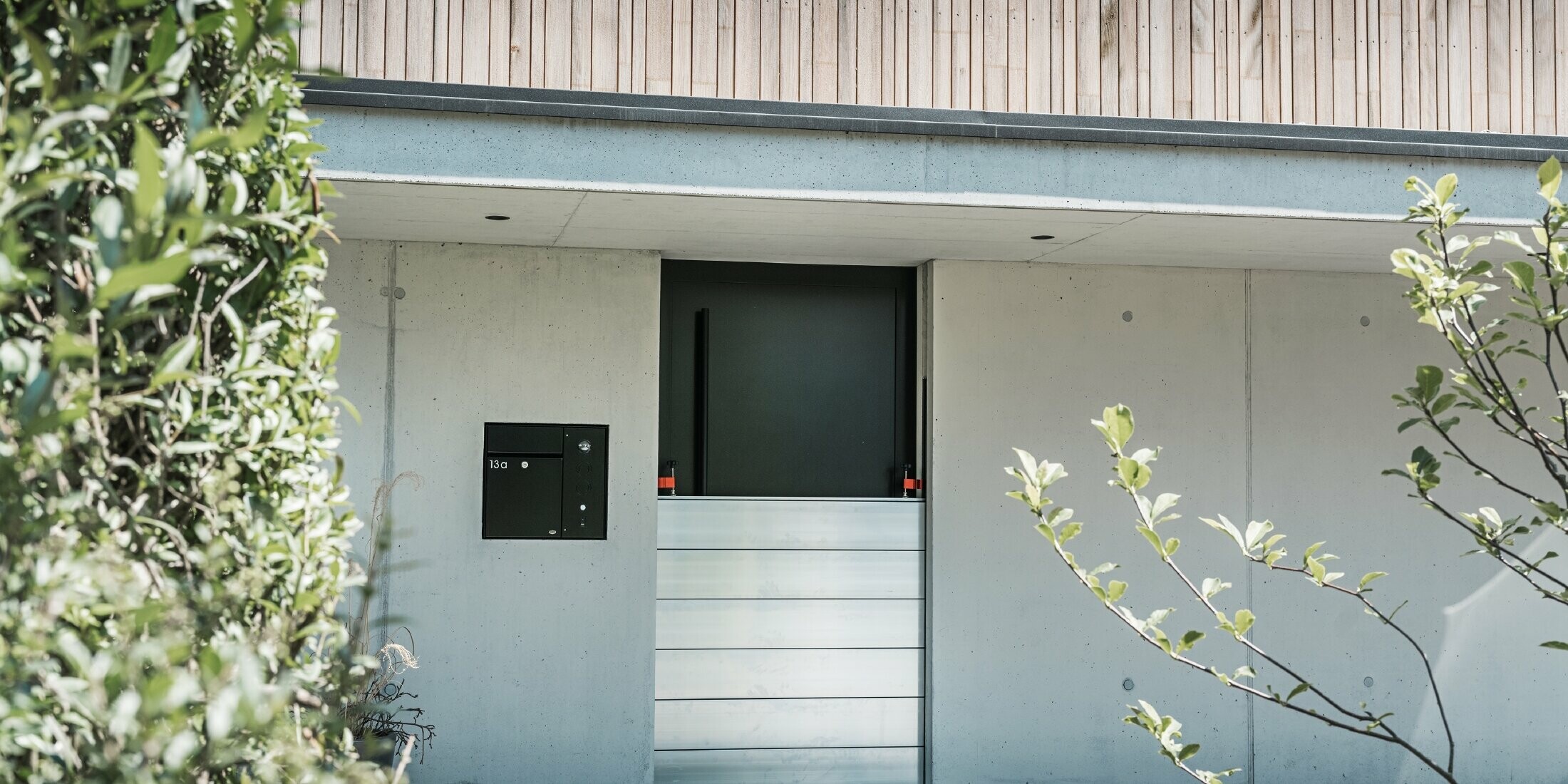 PREFA-hoogwaterbescherming is geïnstalleerd voor de toegangsdeur van een vrijstaand huis met een houten gevel. 