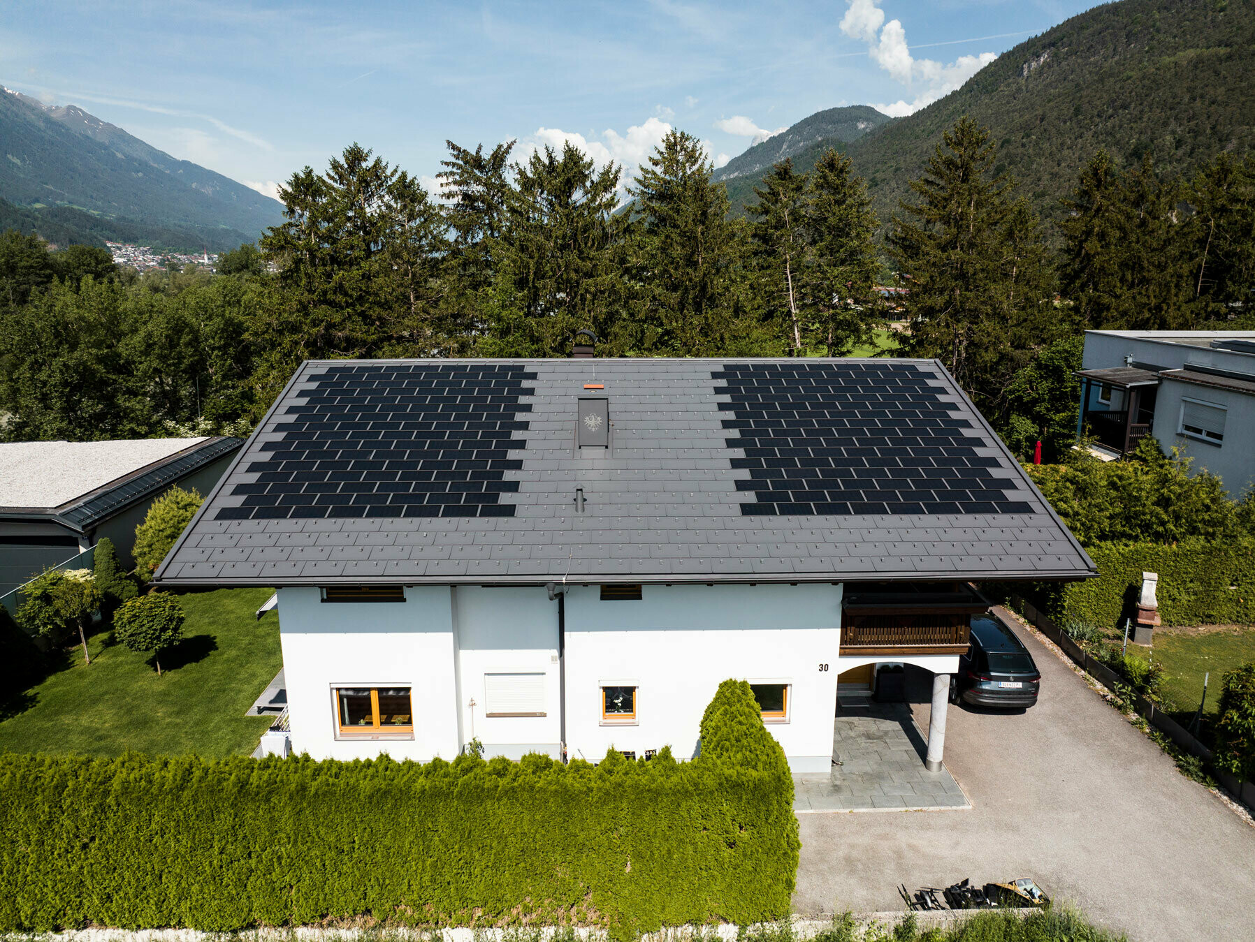 Hier ziet u een eengezinswoning bedekt met de PREFA solar-dakpan klein met dakpan R.16 in de kleur P.10 donkergrijs in een landelijke omgeving.