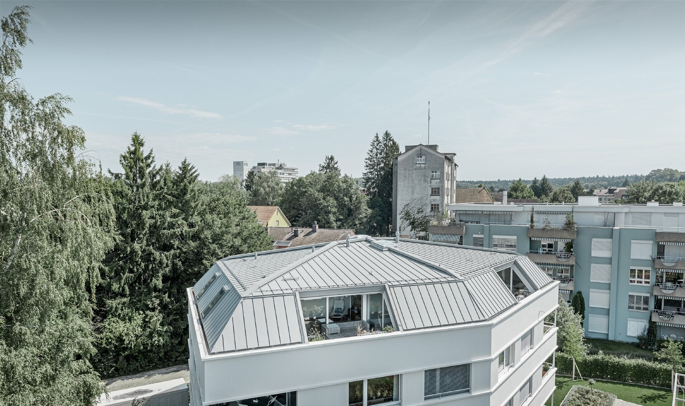 Dak van een woongebouw gedekt met de PREFA Prefalz in patinagrijs met loggia.