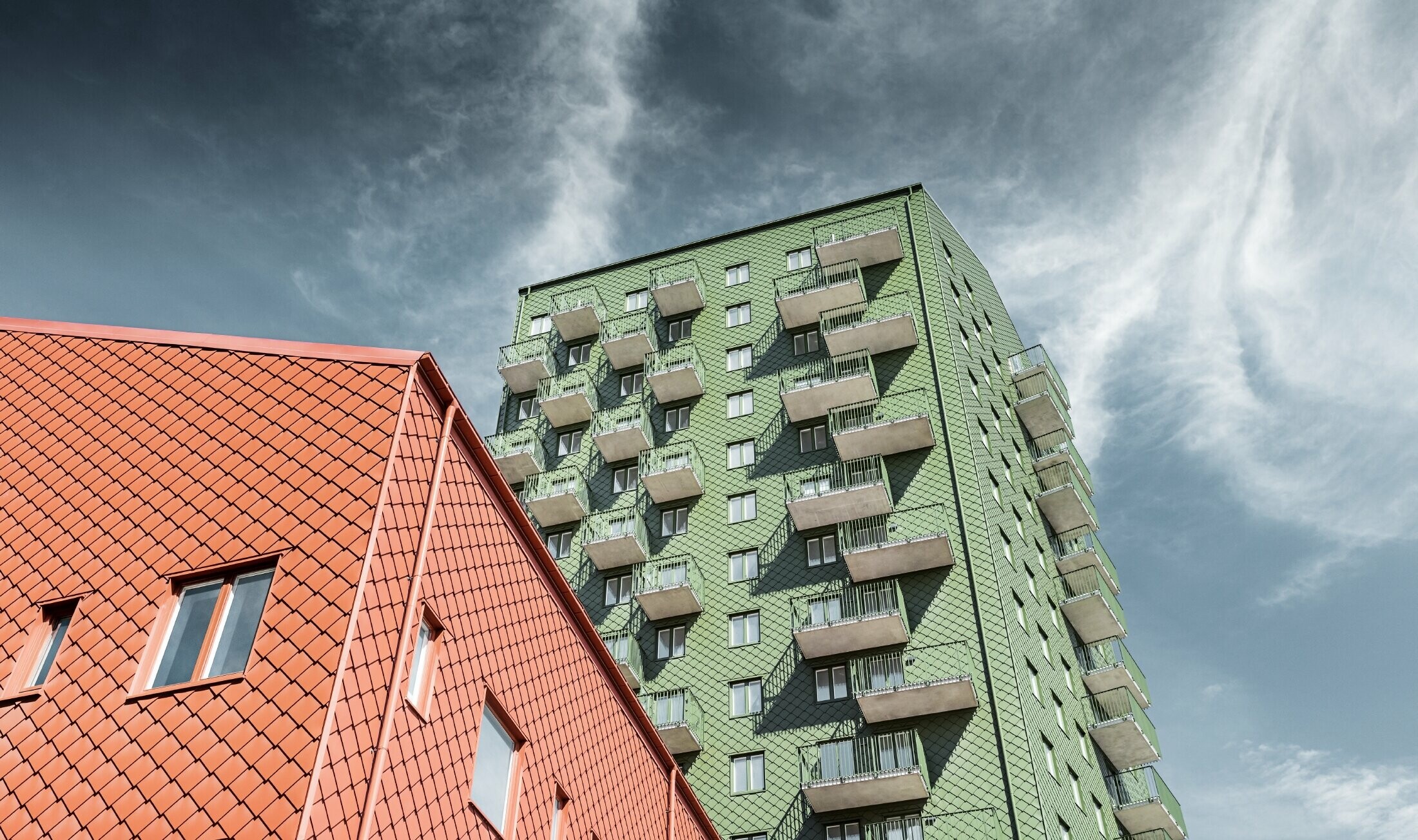 Flatgebouwen met balkons die bekleed zijn met PREFA gevellosange 29 × 29 in olijfgroen en baksteenrood