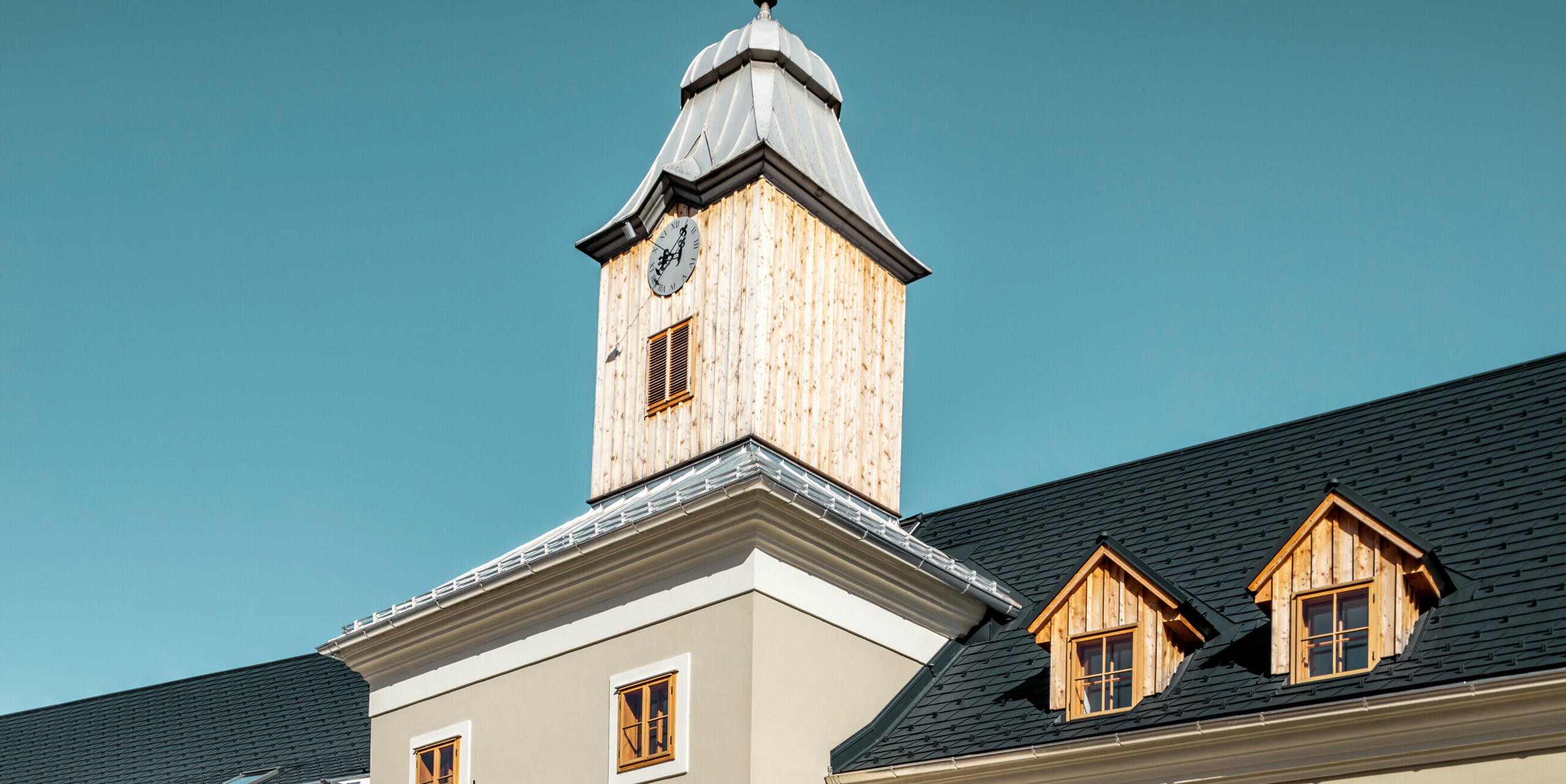 Das Dach des Hotels Glockenturm in Marktl bei Lilienfeld wurde mit der PREFA Dachschindel in P.10 Anthrazit verkleidet. Das PREFA Dachentwässerungssystem des Gebäudes ist in Naturblank gehalten. Unweit vom Hotel Glockenturm liegt das Leopold - unser Wirtshaus. Das Restaurantgebäude wurde ebenfalls mit PREFA Produkten eingedeckt.