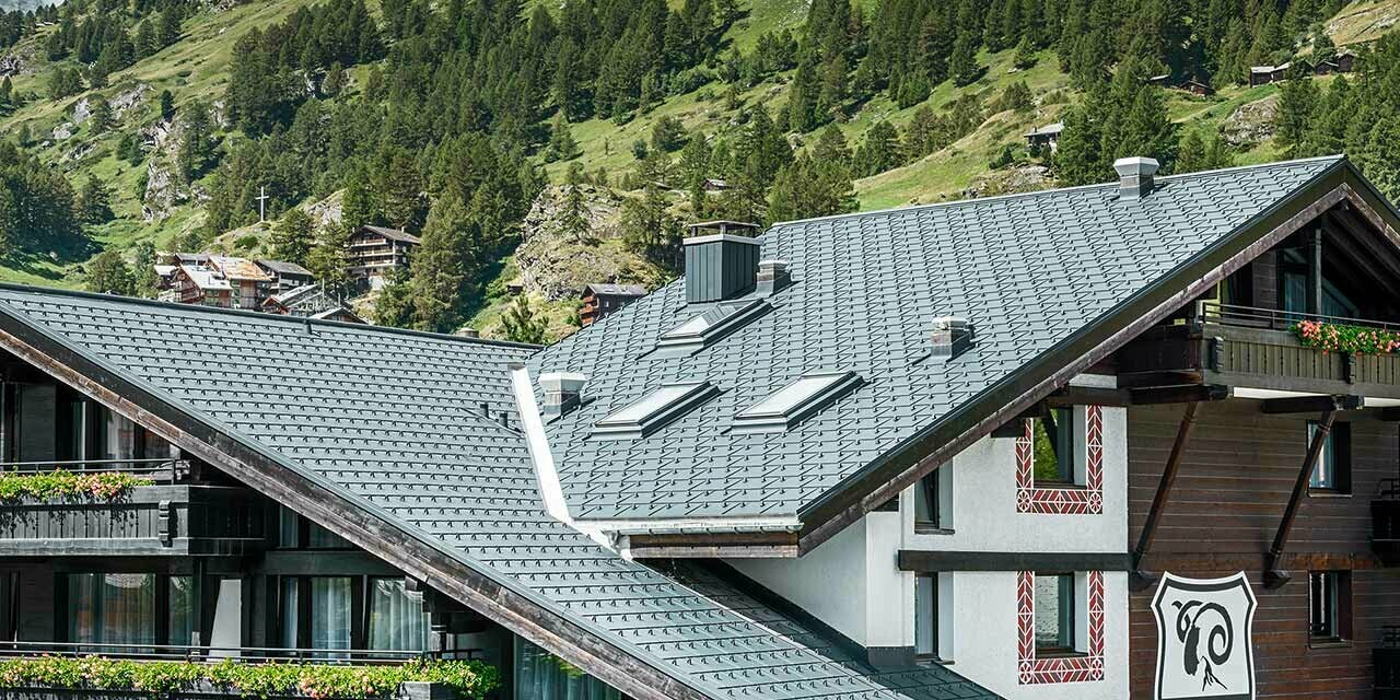 Hotel Alpenhof in Zermatt (Zwitserland) met de Matterhorn op de achtergrond, een gevel en balkons in donker hout en een antracietkleurig aluminiumdak van PREFA