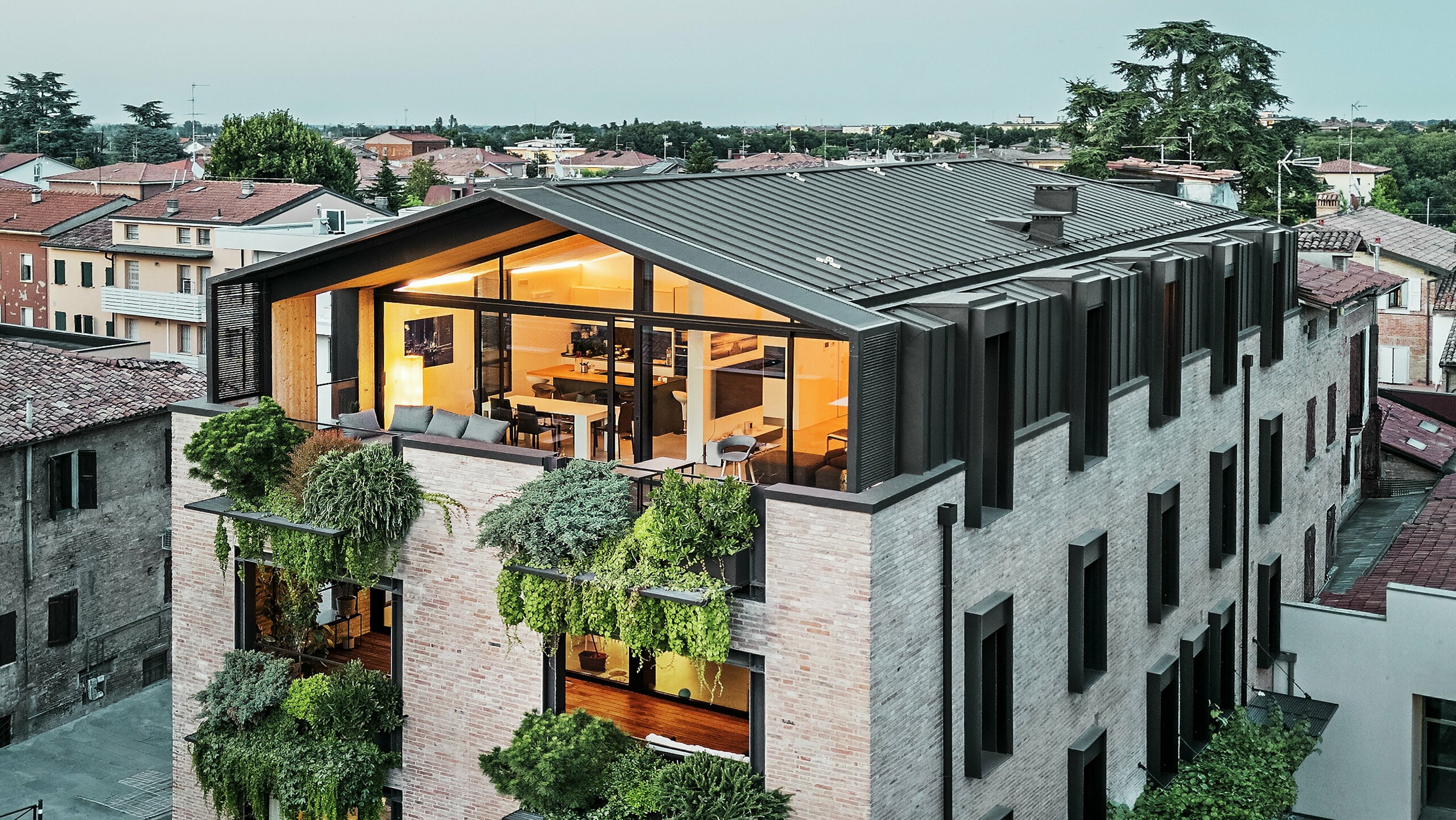 Nachhaltiges Wohnhaus in Italien mit PREFALZ Aluminiumdach und begrünter Backsteinfassade.