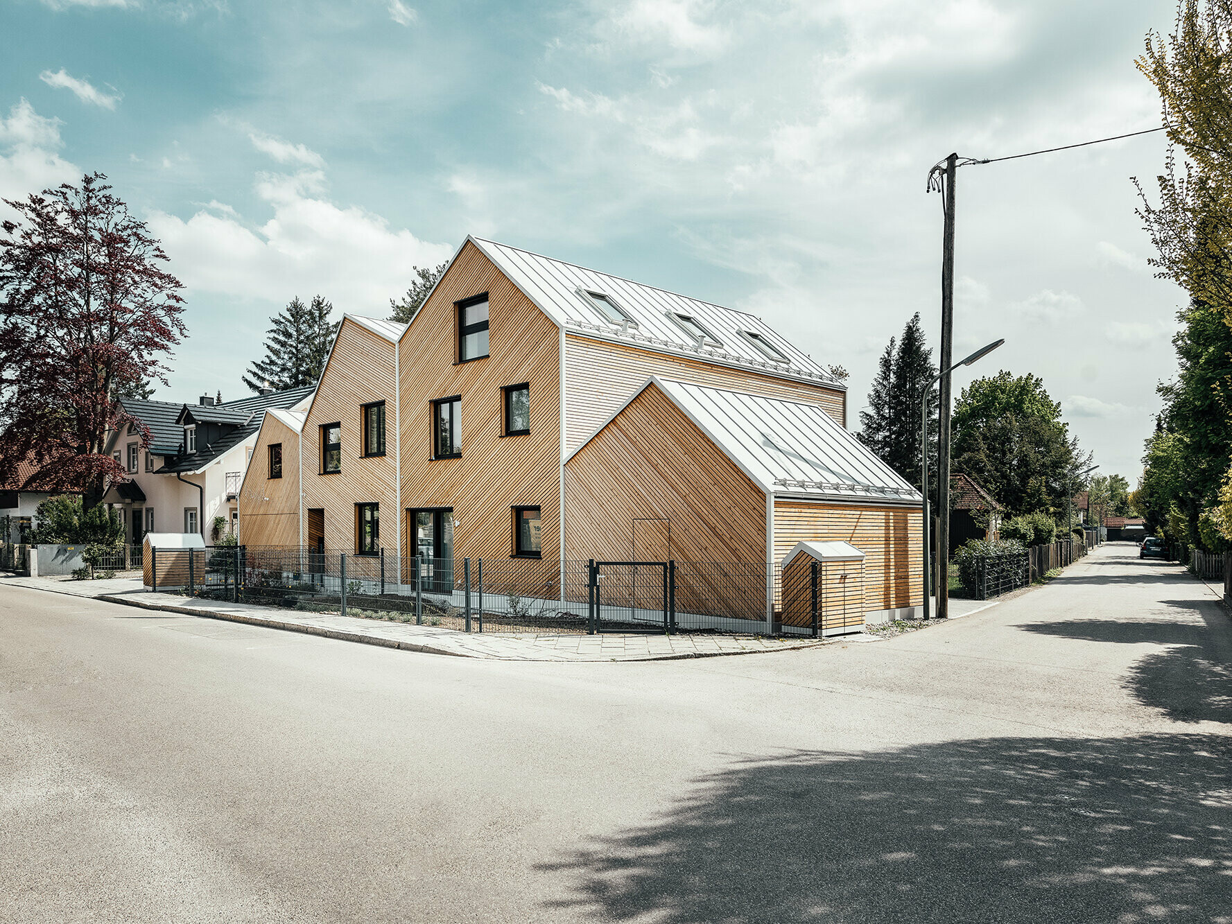 Seitlicher, straßenseitiger Blick auf das Doppelhaus "Hausfuchs", weiße PREFA Dächer mit Prefalz-Bahnen, unregelmäßige Fenster, IFUB*