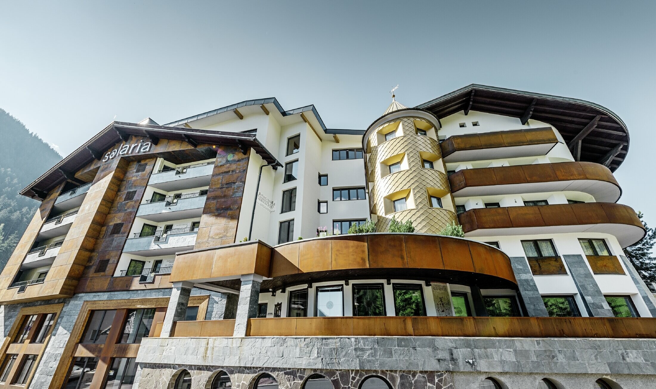 Traditioneel hotel in Ischgl (Oostenrijk) met houten balkonns en gevel en een toren met gouden aluminiumlosanges van PREFA