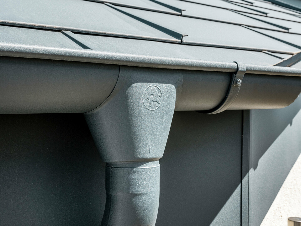 PREFA hanggoot met trechteruitloop en oversteek in P.10 zwart Eengezinswoning in Newel-Besslich met PREFA Dakpan R.16 en PREFA dakafvoersysteem in antraciet