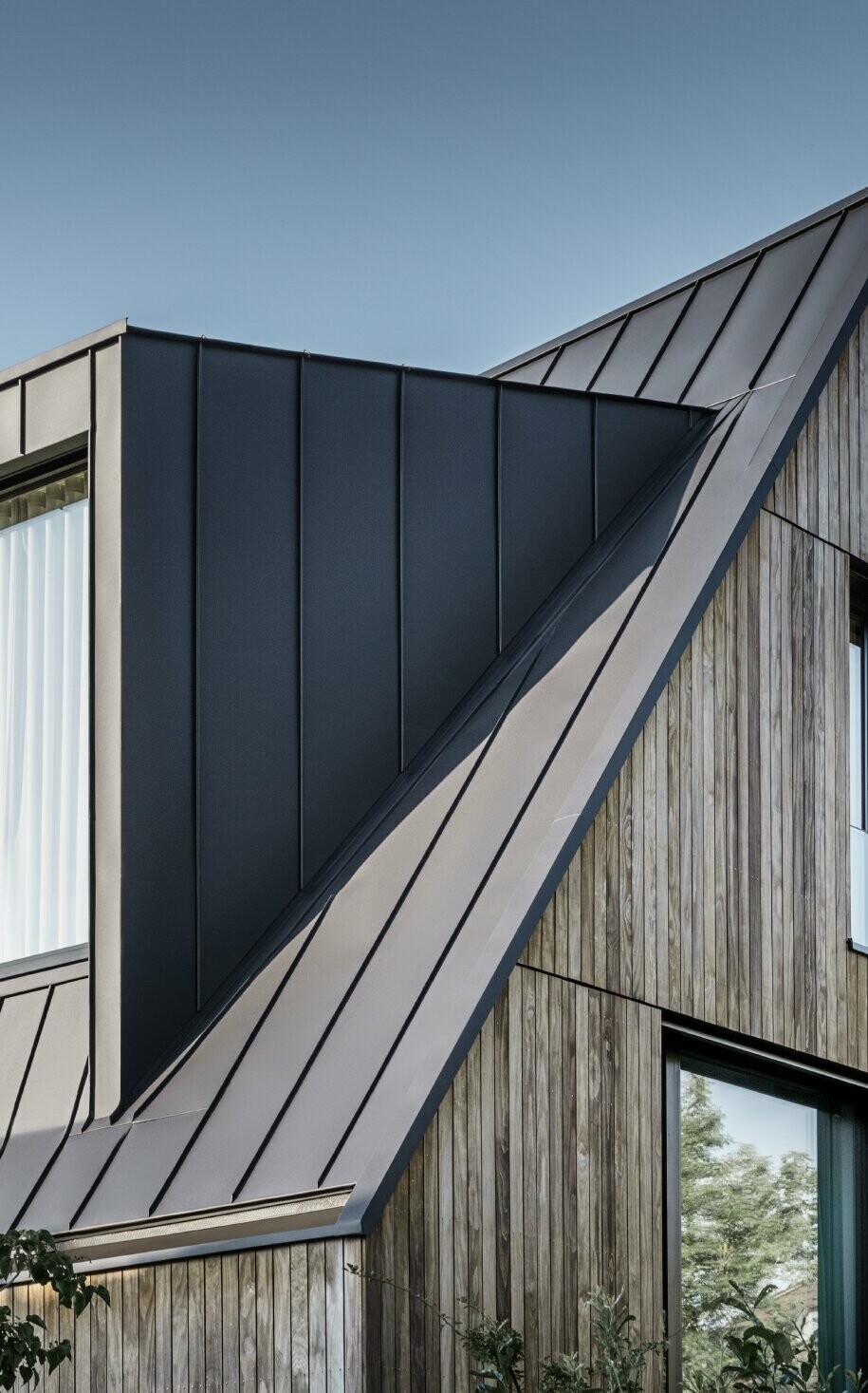 Steil zadeldak met dakkapel, PREFA in P.10 antraciet Steil zadeldak met grote dakkapel, bekleed met PREFALZ van PREFA in antraciet Dak met staande fels gecombineerd met houten gevel