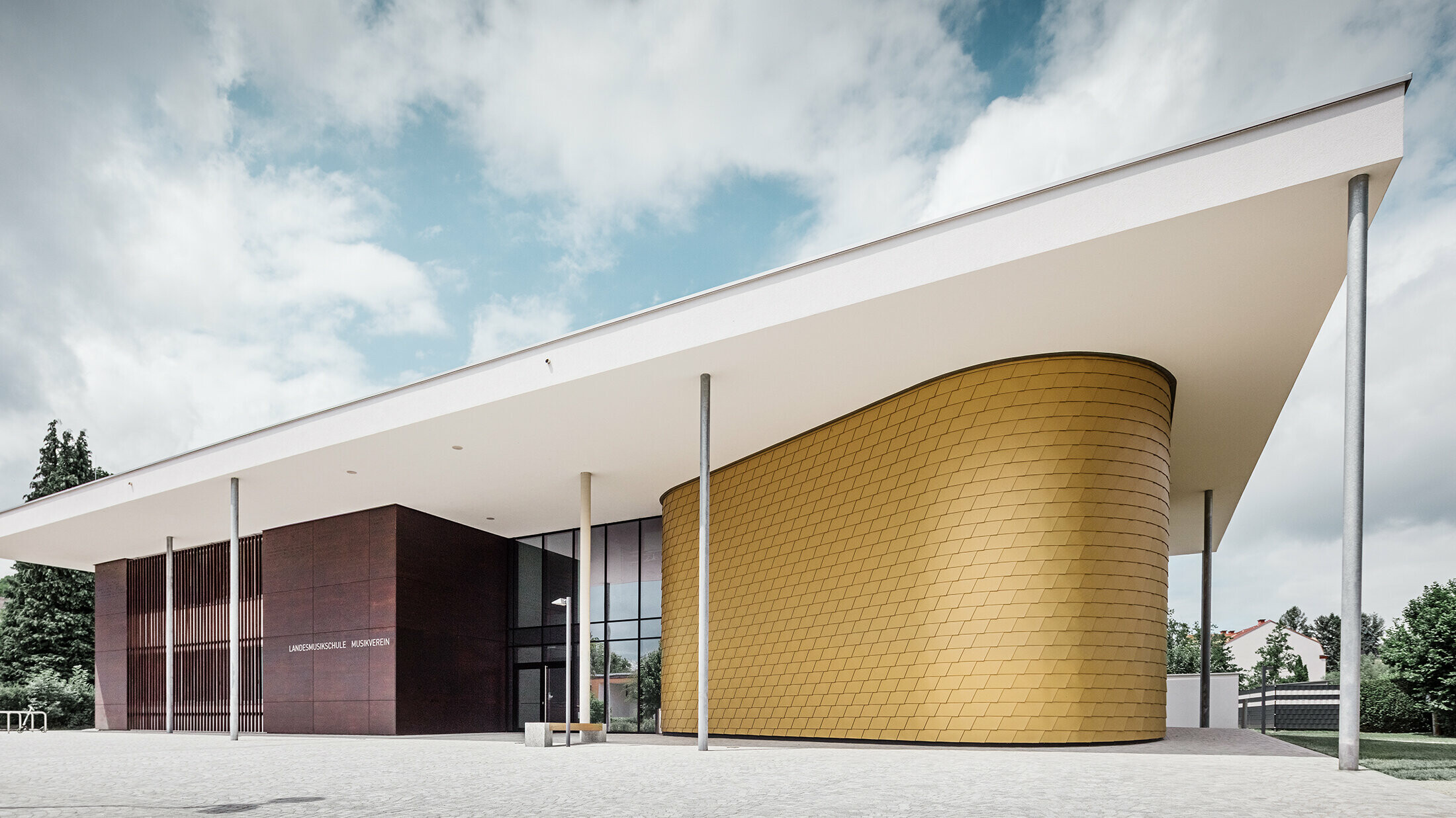 Gouden aluminium dakschindels van PREFA sieren de ronde gevel van de muziekschool