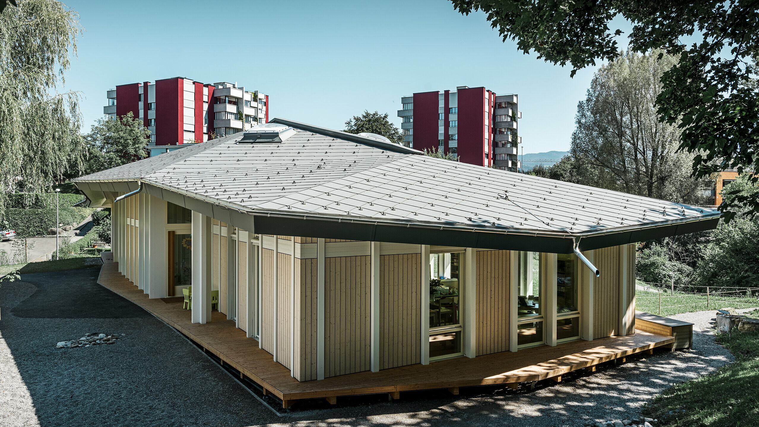 Kleuterschool met één verdieping met verticale gevelpanelen en aluminiumdak van PREFA (daklosange) in lichtgrijs