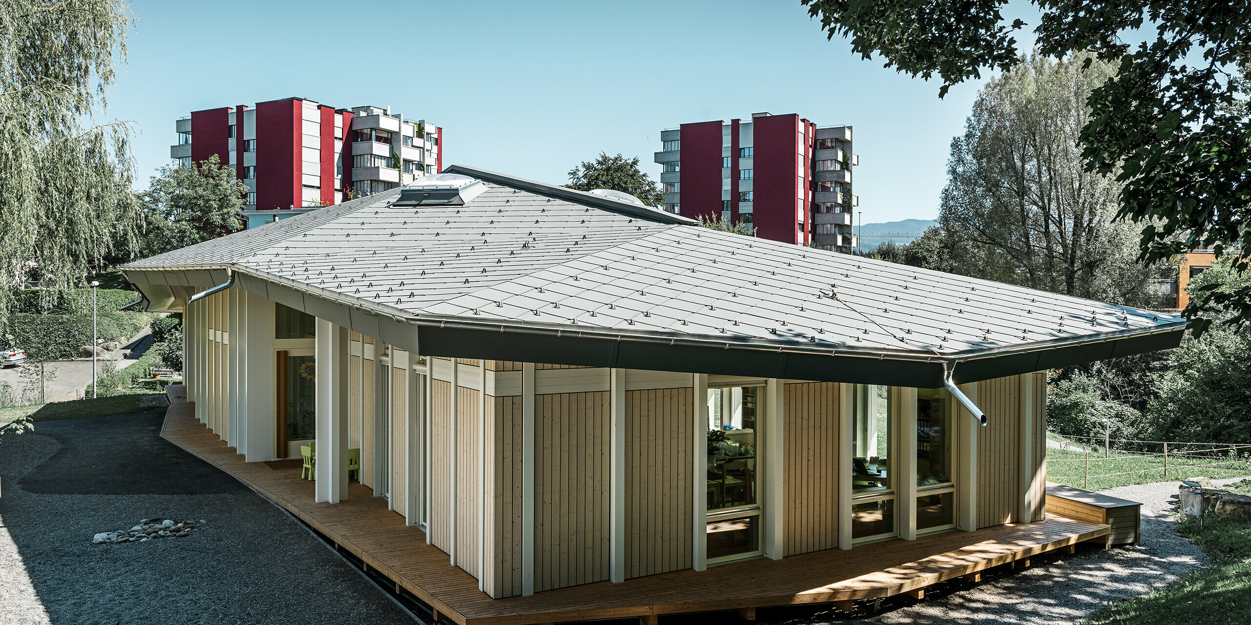 Kleuterschool met één verdieping met verticale gevelpanelen en aluminiumdak van PREFA (daklosange) in lichtgrijs