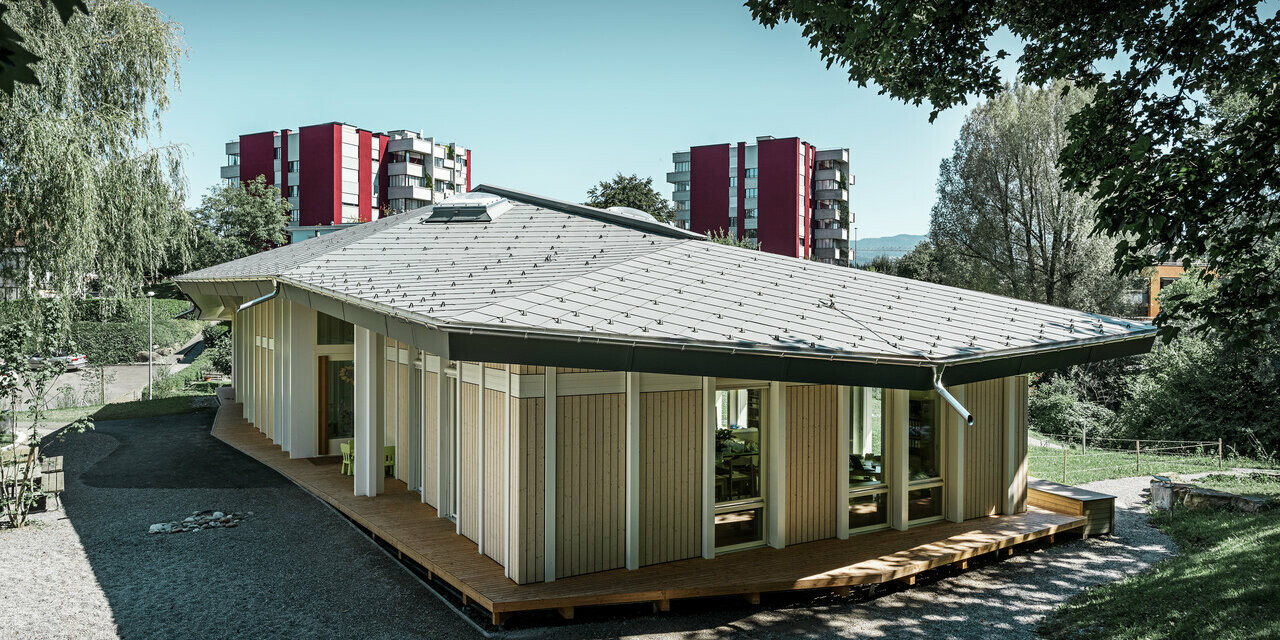 Kleuterschool met één verdieping met verticale gevelpanelen en aluminiumdak van PREFA (daklosange) in lichtgrijs